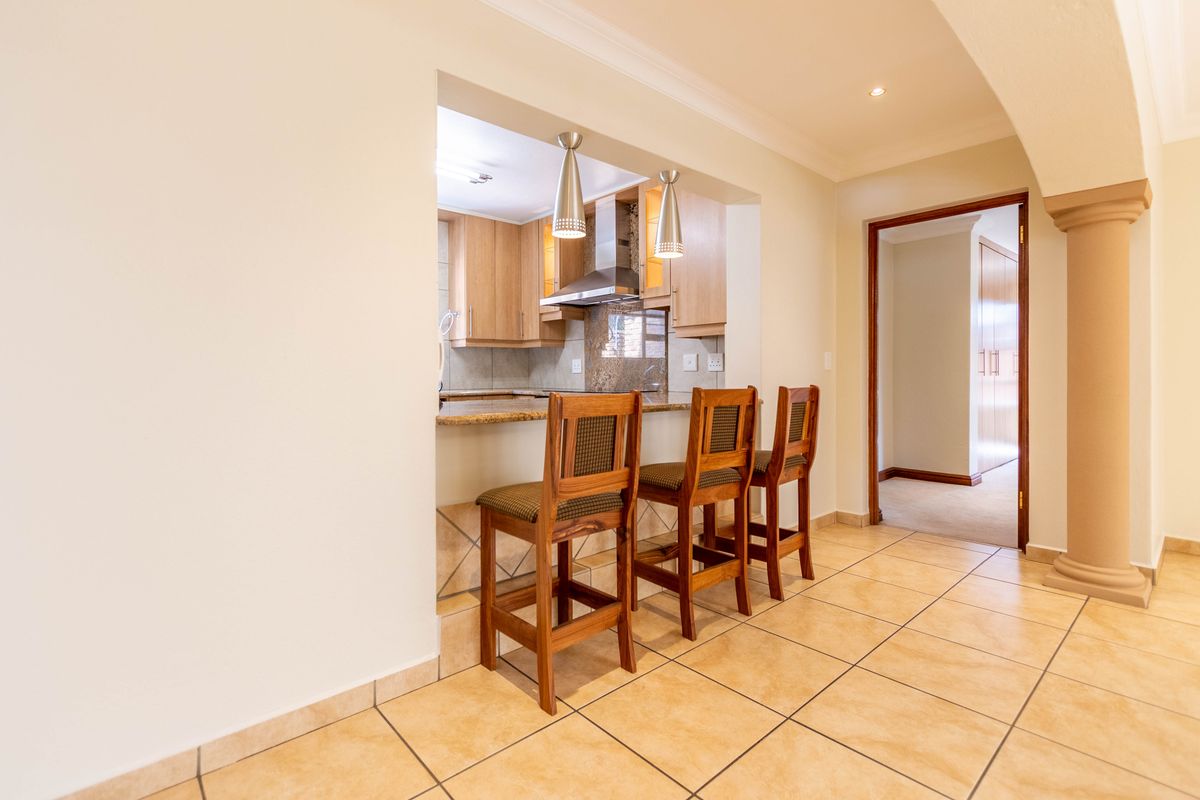 A view of a kitchen pass-through with a breakfast bar counter, tiled flooring, and an arched entryway leading to a hallway.