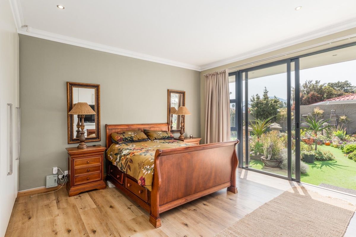 Spacious bedroom featuring light wood-look flooring, built-in wardrobes, and large sliding glass doors providing direct access to the private rear garden.