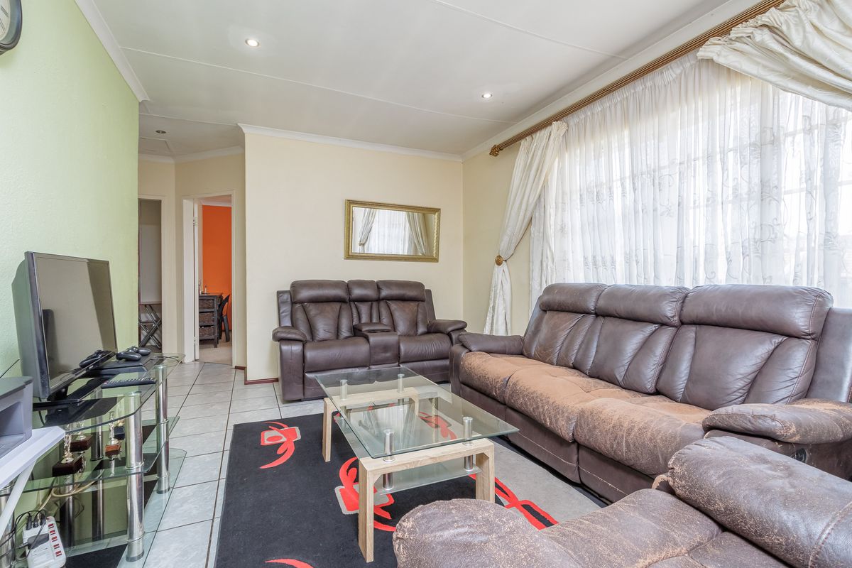 A well-lit living room featuring tiled flooring, recessed downlighting, and coved cornicing, providing a functional and comfortable space for relaxation.