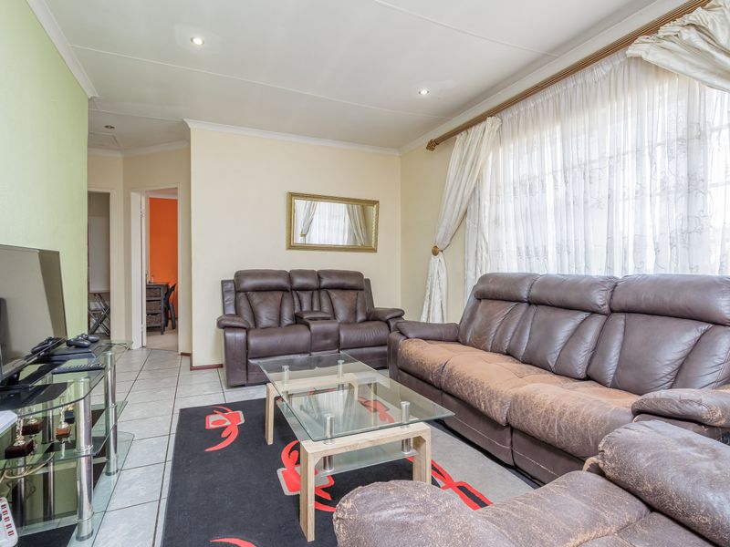 A well-lit living room featuring tiled flooring, recessed downlighting, and coved cornicing, providing a functional and comfortable space for relaxation.