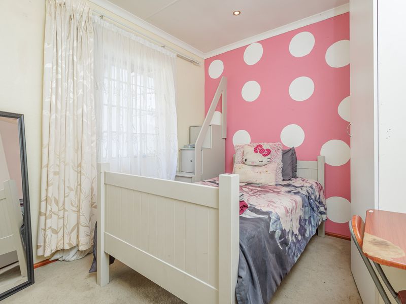 A bedroom featuring a built-in wardrobe, recessed downlighting, and decorative coving, currently styled with a polka-dot feature wall.