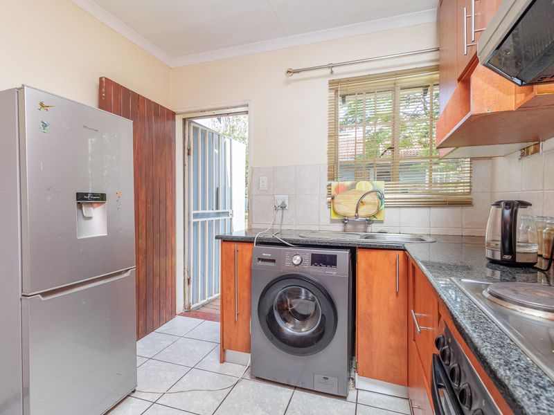 Functional kitchen featuring laminate cabinetry, granite countertops, built-in oven, hob, extractor fan, and direct access to the exterior via a security gate.
