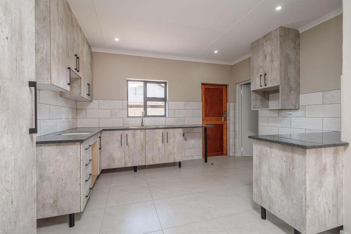 Modern kitchen featuring light wood-look cabinetry, dark granite countertops, subway tile backsplash, and tiled flooring with recessed ceiling lighting.
