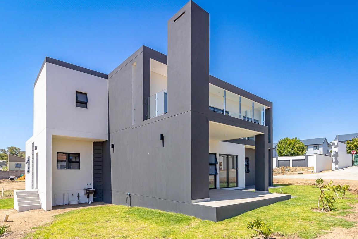 Modern two-story residential home featuring a contemporary architectural design, clean lines, a spacious balcony, and a ground-level patio area.