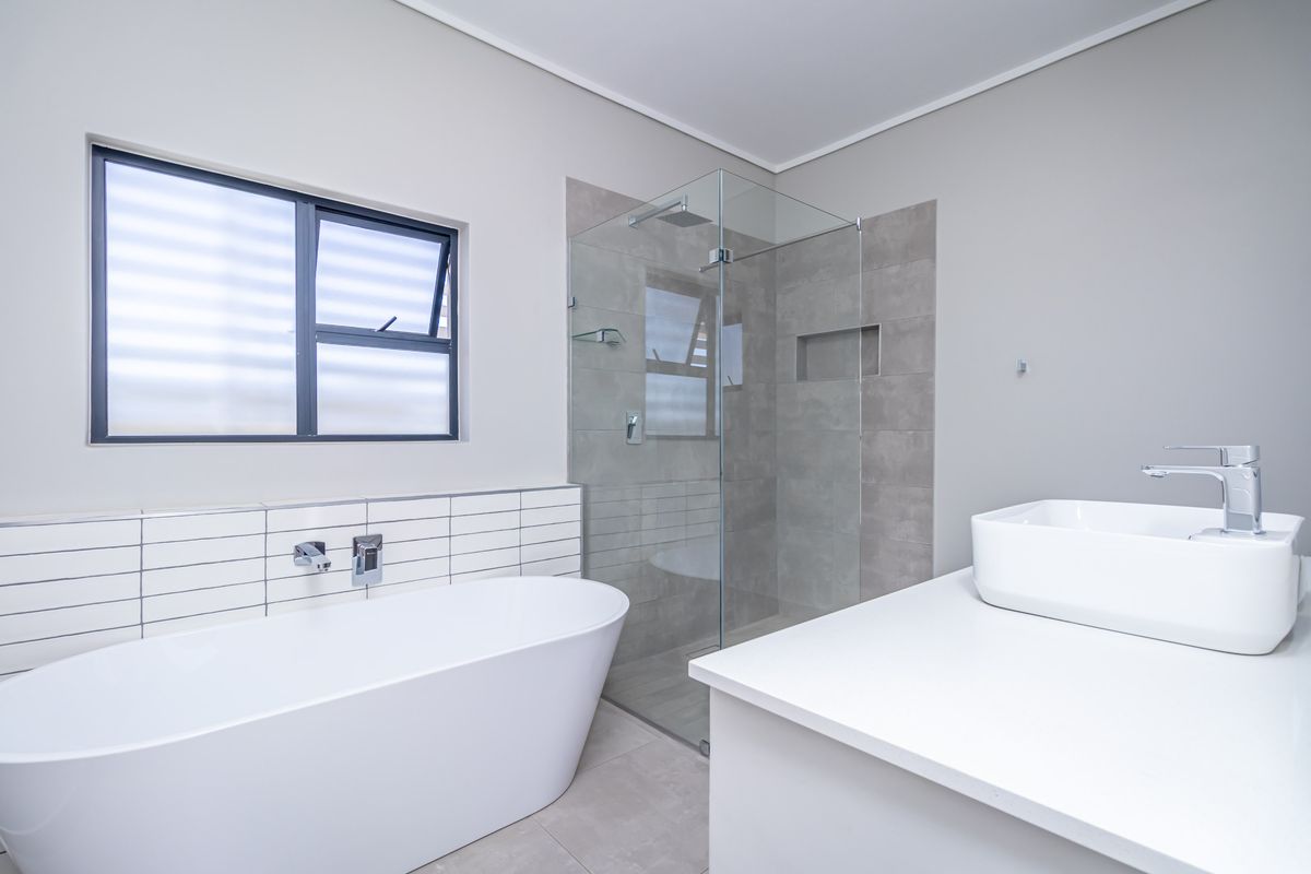Modern bathroom featuring a freestanding bathtub, a glass-enclosed walk-in shower with tiled walls, and a contemporary vanity with a vessel sink.