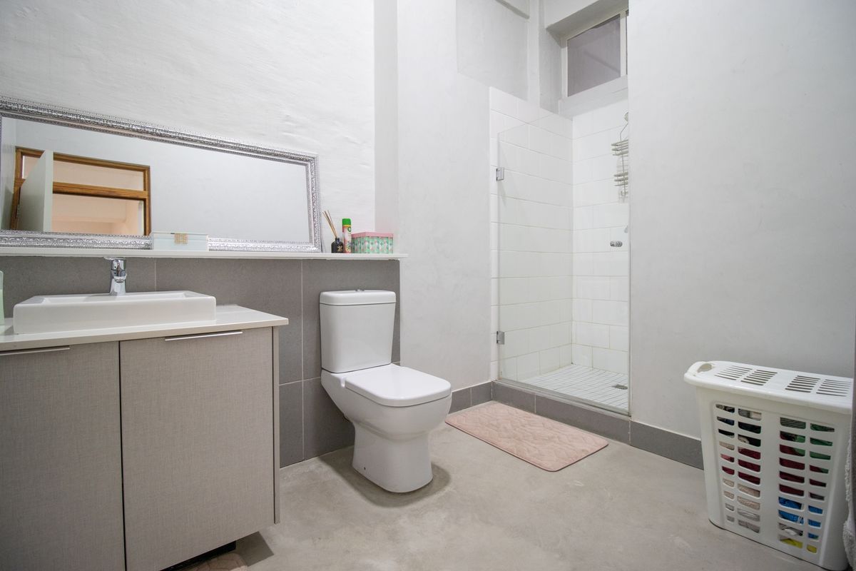 A modern bathroom featuring a floating vanity with a vessel sink, a wall-mounted toilet, and a walk-in shower with a glass enclosure.