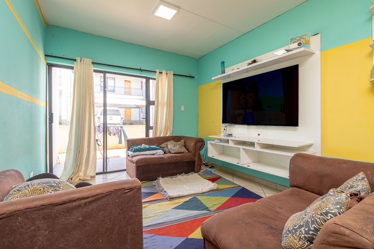 A living room featuring tiled flooring, a built-in media console, and sliding glass doors providing access to an outdoor area.