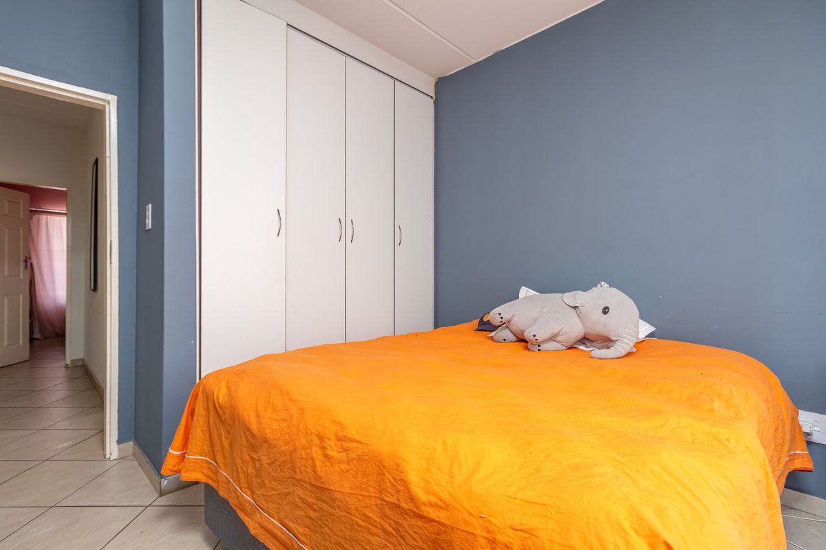 A bedroom featuring built-in floor-to-ceiling wardrobes and tiled flooring, with direct access to an adjacent hallway.