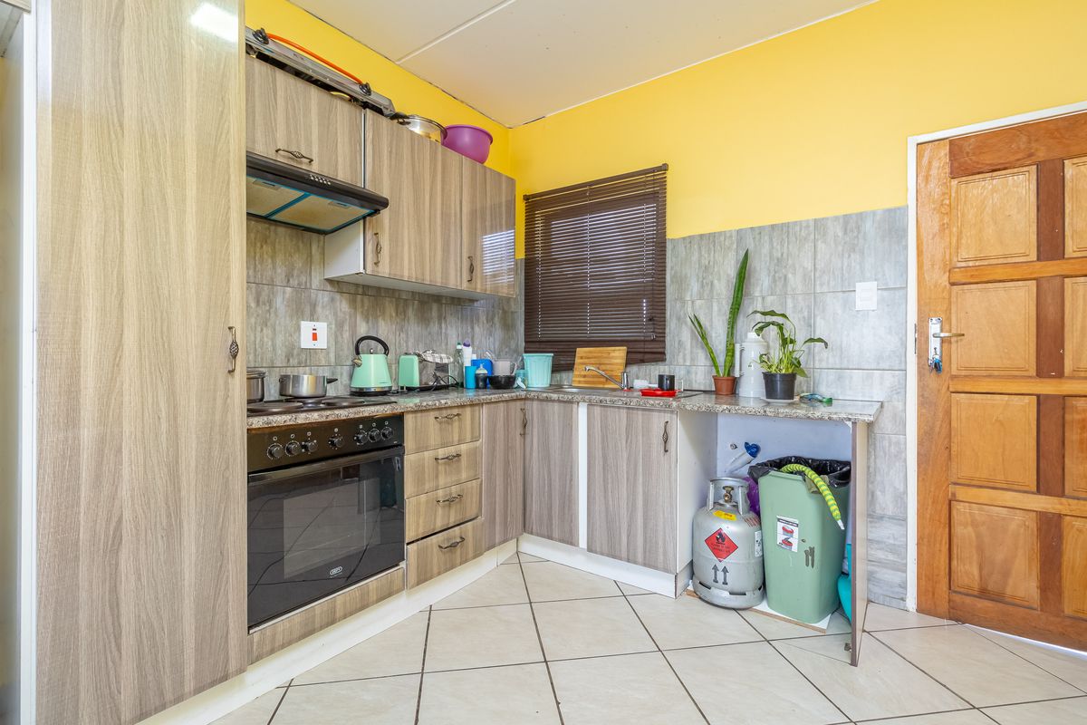 A functional kitchen featuring wood-look cabinetry, built-in oven and hob, tiled splashbacks, and tiled flooring.