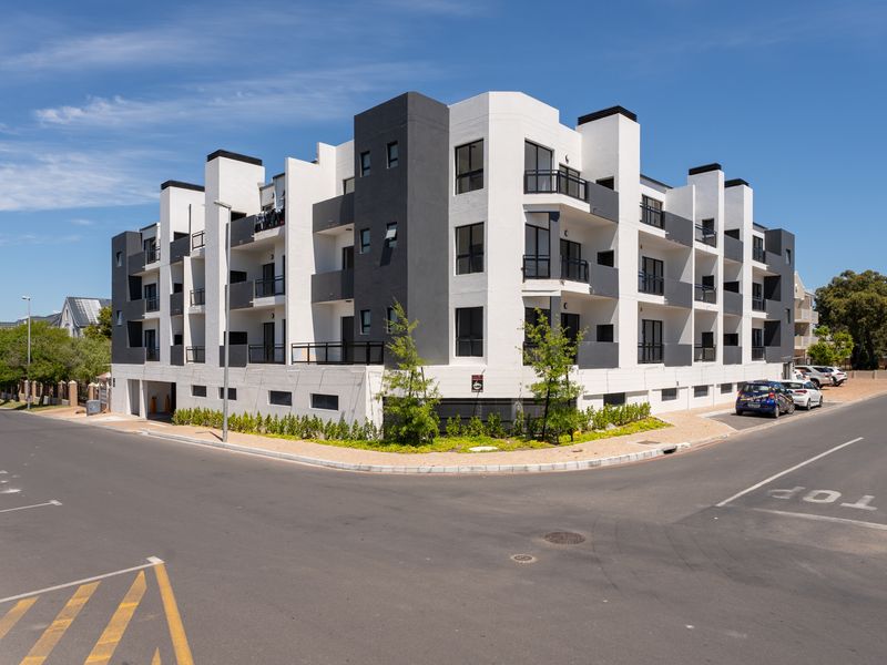 Modern multi-story apartment building featuring a contemporary white and charcoal facade with private balconies and integrated street-level parking.