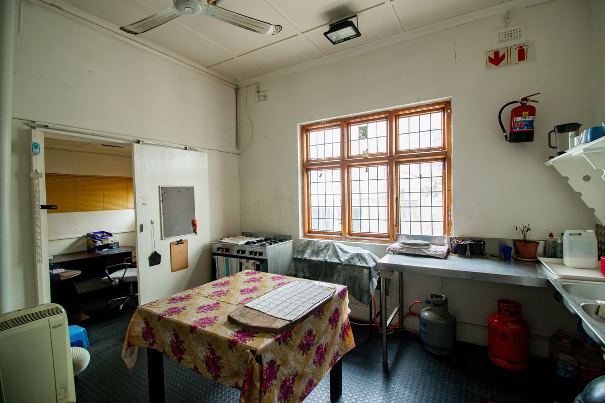A functional kitchen area featuring a gas stove, stainless steel prep surfaces, and a large window, suitable for a commercial or utility workspace.