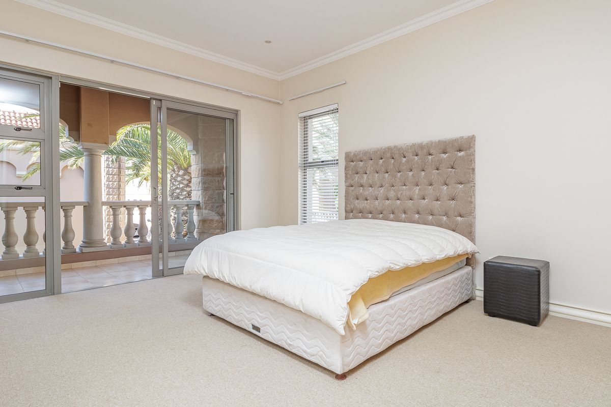 Spacious bedroom featuring neutral carpeting, crown molding, and large sliding glass doors providing direct access to a private balcony.