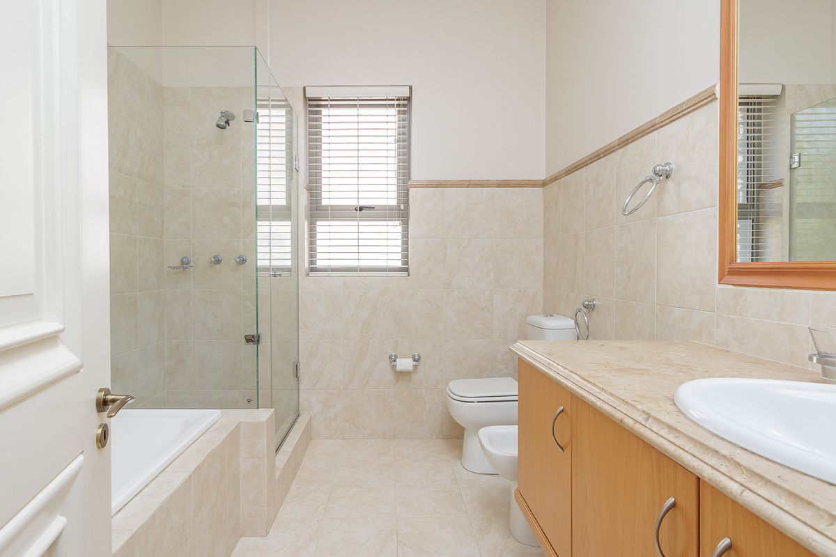 A well-maintained bathroom featuring a glass-enclosed shower, a built-in bathtub, a vanity with a stone countertop, a toilet, and a bidet.