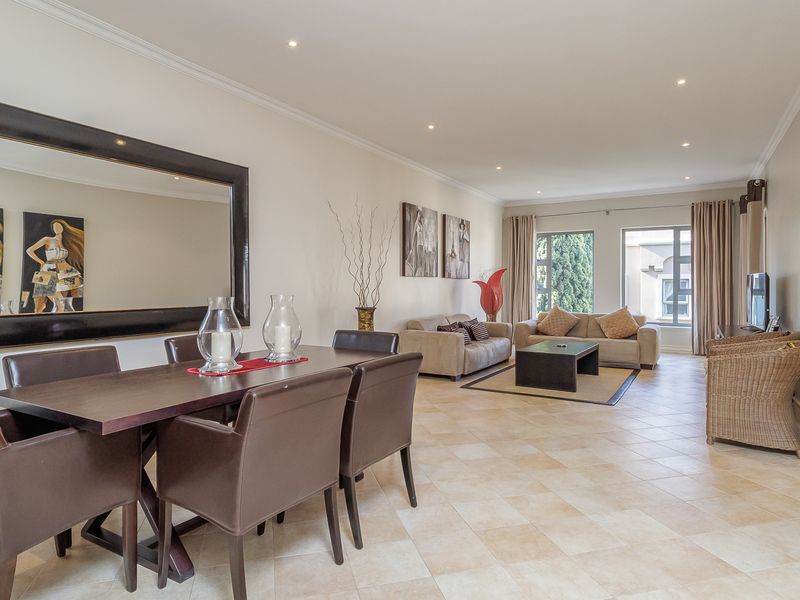 Spacious open-plan living and dining area featuring tiled flooring, recessed downlighting, and large windows providing natural light.