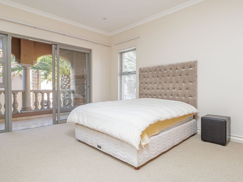 Spacious bedroom featuring neutral carpeting, crown molding, and large sliding glass doors providing direct access to a private balcony.