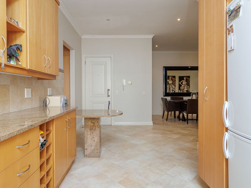 A functional kitchen featuring light wood cabinetry, granite countertops, and tiled flooring, with an open-plan layout leading into the dining area.