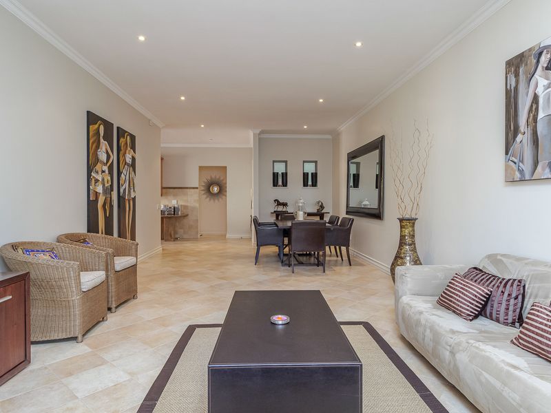 Spacious open-plan living and dining area featuring neutral tiled flooring, recessed downlighting, and a seamless flow towards the kitchen area.