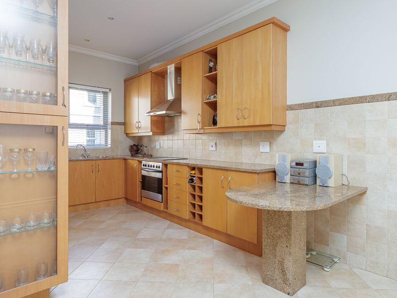 A functional kitchen featuring light wood cabinetry, granite countertops, a built-in oven with extractor fan, and tiled flooring.