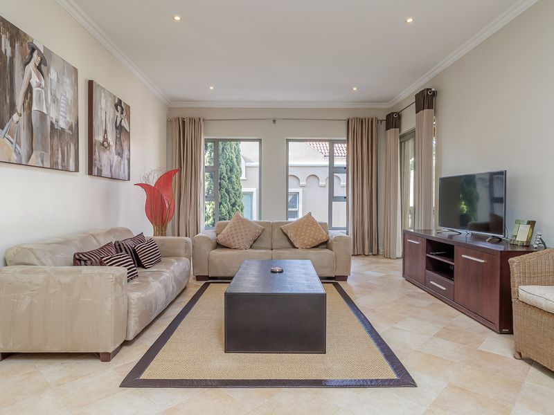 A well-maintained living room featuring tiled flooring, recessed ceiling lighting, and large windows that provide natural light and access to the outdoor area.