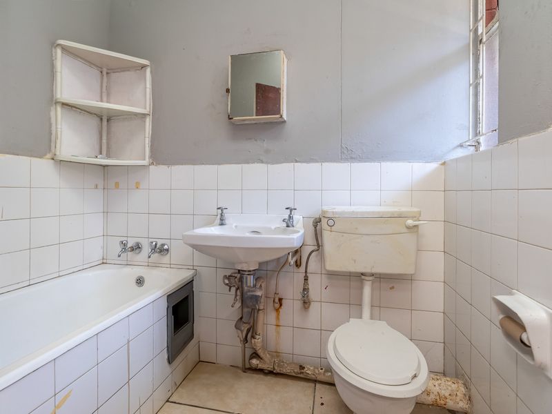A dated bathroom featuring a bathtub, pedestal basin, and toilet, requiring significant renovation and modernization of fixtures and finishes.
