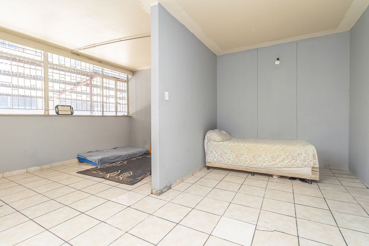 A bedroom space featuring tiled flooring and a partition wall, requiring cosmetic updates and finishing touches to improve its overall condition and appeal.