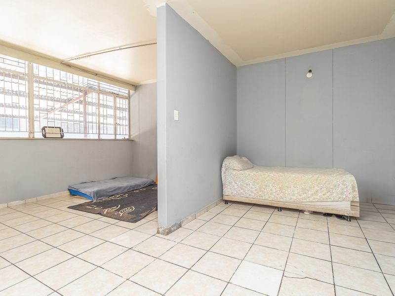 A bedroom space featuring tiled flooring and a partition wall, requiring cosmetic updates and finishing touches to improve its overall condition and appeal.
