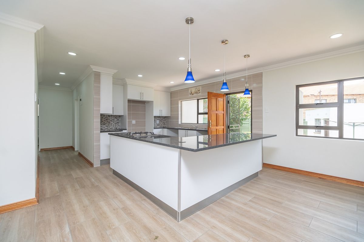 Modern open-plan kitchen featuring a central island with a gas hob, granite countertops, and sleek cabinetry, seamlessly integrated into the living space.