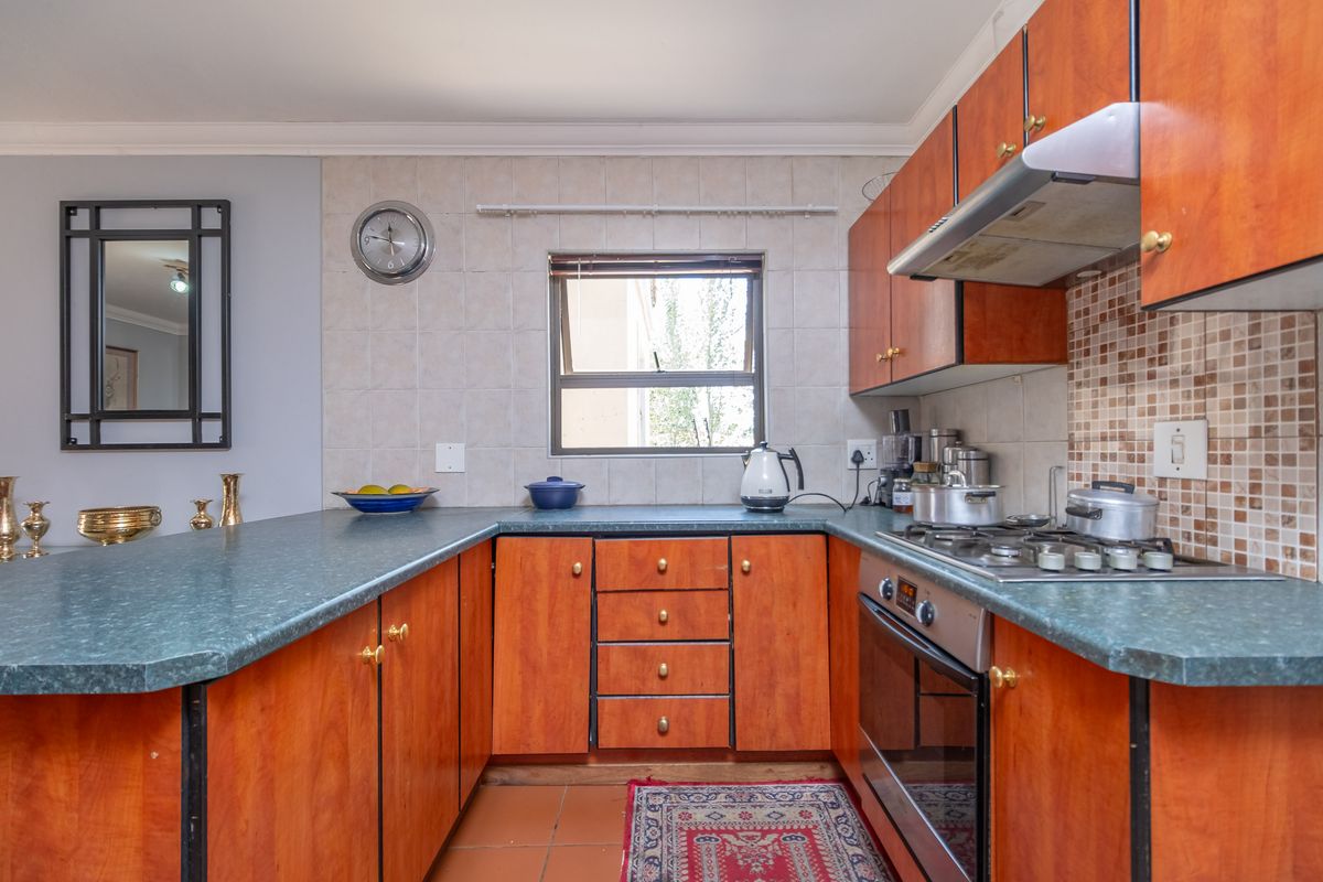 Functional kitchen featuring wooden cabinetry, a gas hob with extractor fan, built-in oven, and a breakfast bar counter.
