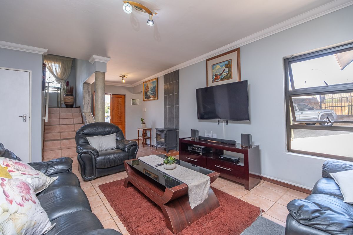 Spacious living room featuring tiled flooring, a built-in fireplace with tiled surround, and a staircase leading to the upper level.
