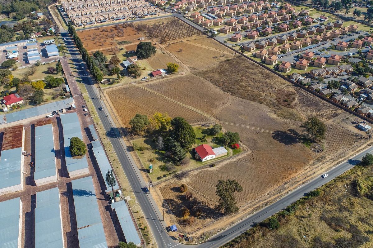 Aerial view of a large residential vacant land parcel featuring established trees, existing structures, and direct road access within a developed suburban area.