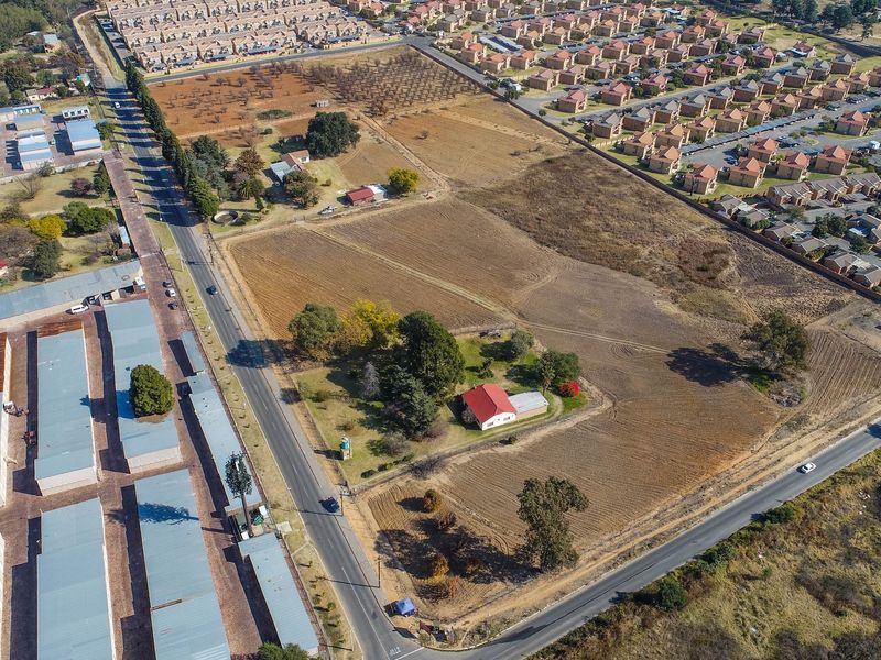 Aerial view of a large residential vacant land parcel featuring established trees, existing structures, and direct road access within a developed suburban area.