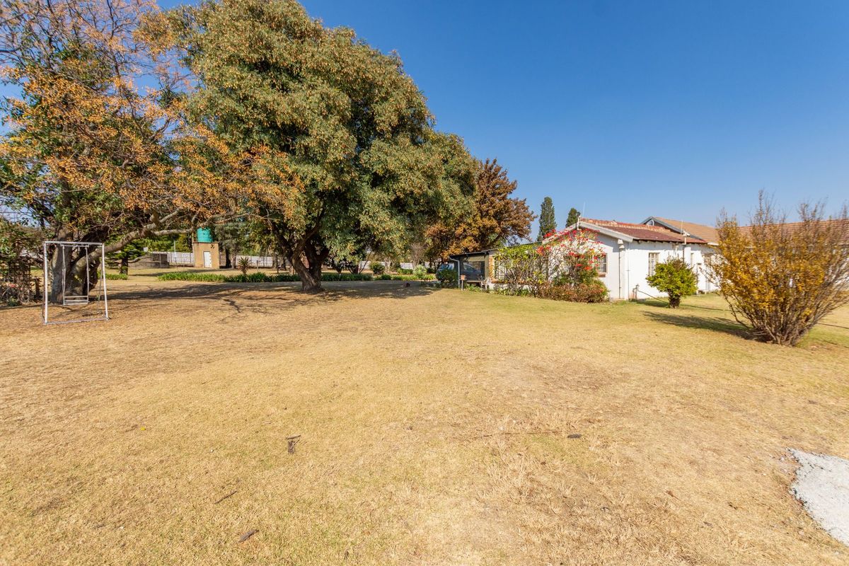 A spacious rear garden area featuring established trees, a large lawn, and a water tank, providing ample outdoor space.