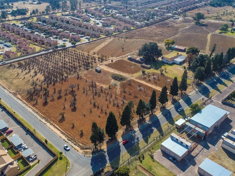 An aerial view of a large, vacant residential land parcel featuring mature trees, perimeter fencing, and convenient access to surrounding suburban infrastructure.