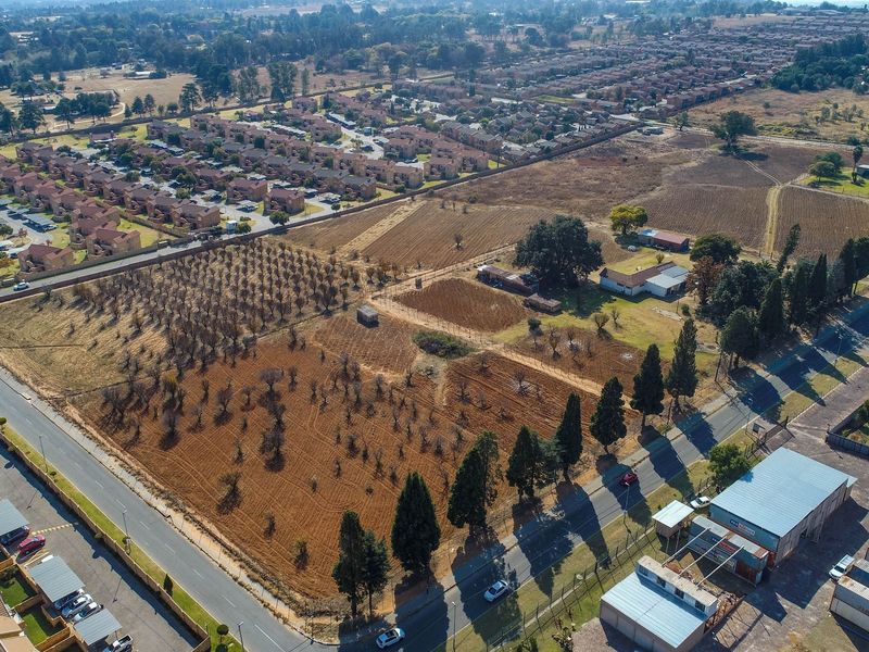 Aerial view of a large vacant residential land parcel featuring established trees, perimeter fencing, and convenient access to surrounding suburban infrastructure.