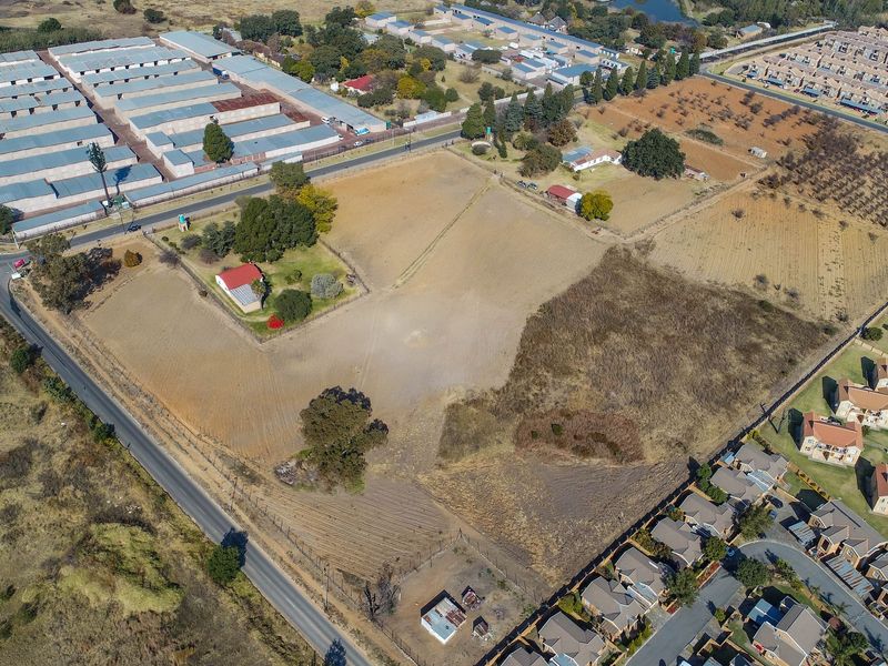An aerial view of a large, vacant residential land parcel situated in a developed suburban area with surrounding infrastructure and access roads.