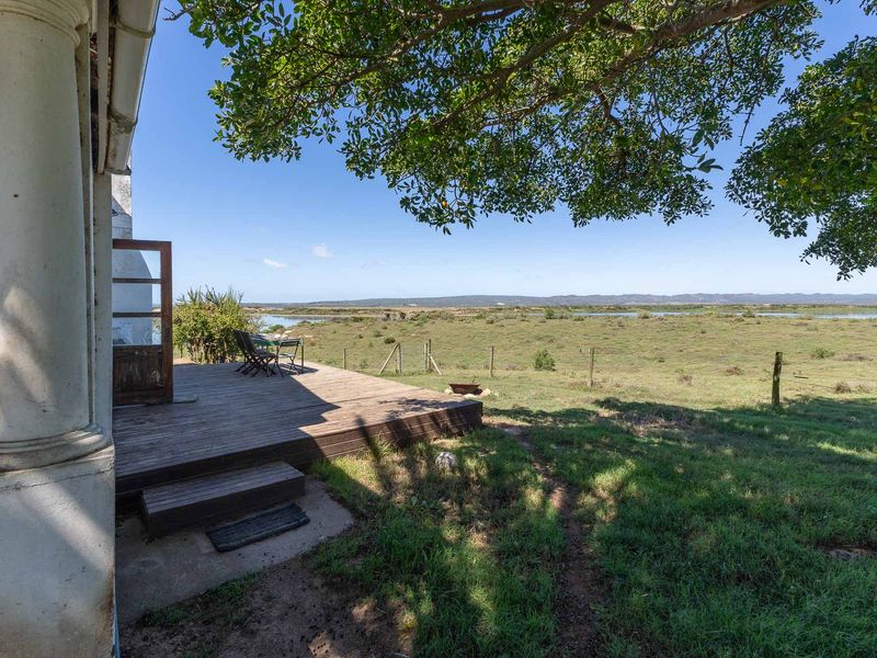 A wooden deck patio overlooking expansive rural landscape and water views, featuring a classic column support and direct access to the garden.