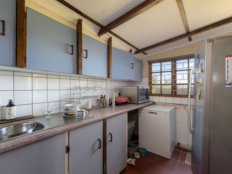 A functional kitchen featuring laminate countertops, tiled backsplash, and exposed timber ceiling beams, offering potential for modernization and cosmetic updates.