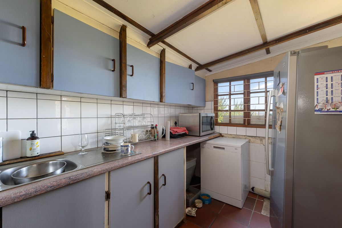 A functional kitchen featuring laminate countertops, tiled backsplash, and exposed timber ceiling beams, offering potential for modernization and cosmetic updates.