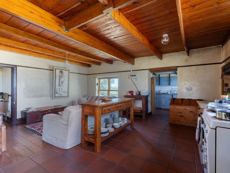 Open plan living and kitchen area featuring exposed timber beam ceilings, terracotta tiling, and rustic finishes, offering a warm and traditional farm-style atmosphere.