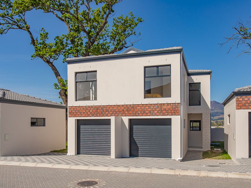 Modern double-story townhouse featuring a double garage, brick and plaster facade, and paved driveway in a well-maintained residential estate.