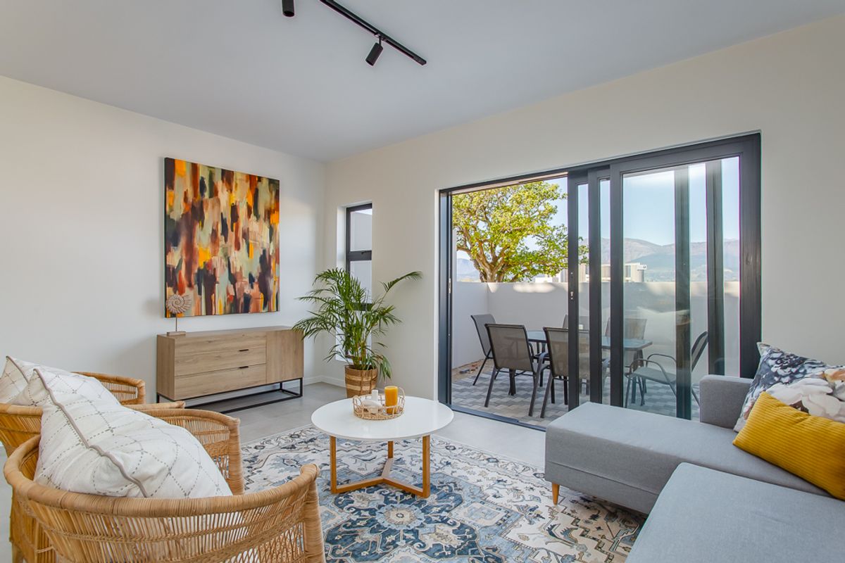 Bright living room featuring modern track lighting and large sliding glass doors that open onto a private balcony with scenic views.