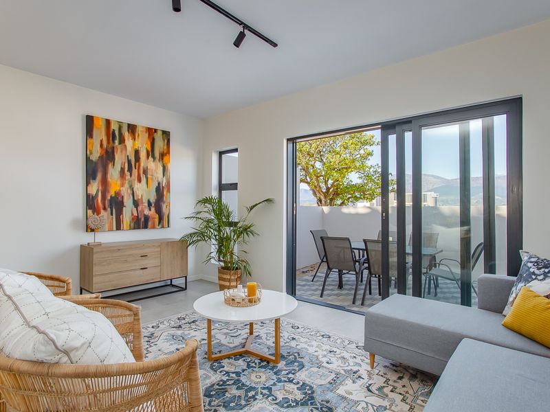 Bright living room featuring modern track lighting and large sliding glass doors that open onto a private balcony with scenic views.