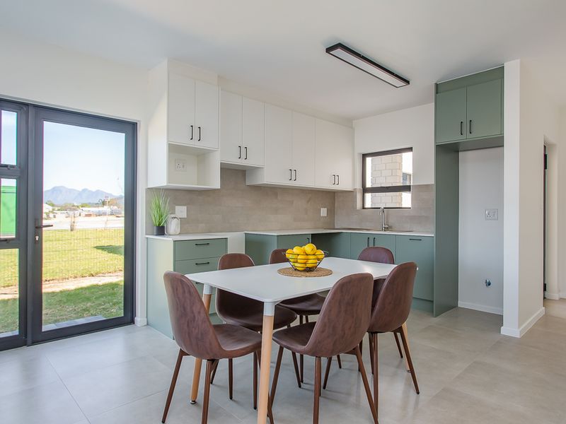 Modern open-plan kitchen featuring two-tone cabinetry, tiled backsplash, and direct access to the garden through a glass door.