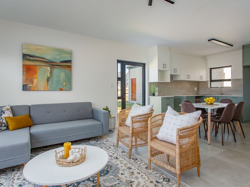 Open-plan living and dining area featuring a modern kitchen with built-in cabinetry, tiled flooring, and direct access to the exterior.