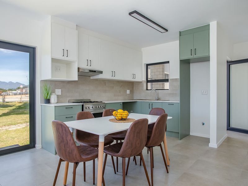 Modern open-plan kitchen featuring two-tone cabinetry, integrated gas hob, extractor fan, and tiled flooring with direct access to the outdoor area.