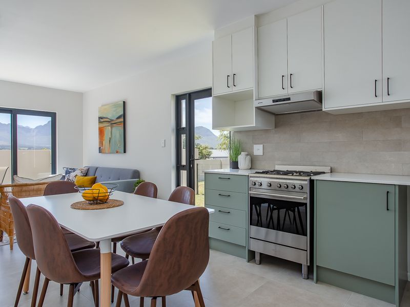 Modern open-plan kitchen and dining area featuring contemporary cabinetry, a gas stove with extractor fan, and seamless access to an outdoor patio.