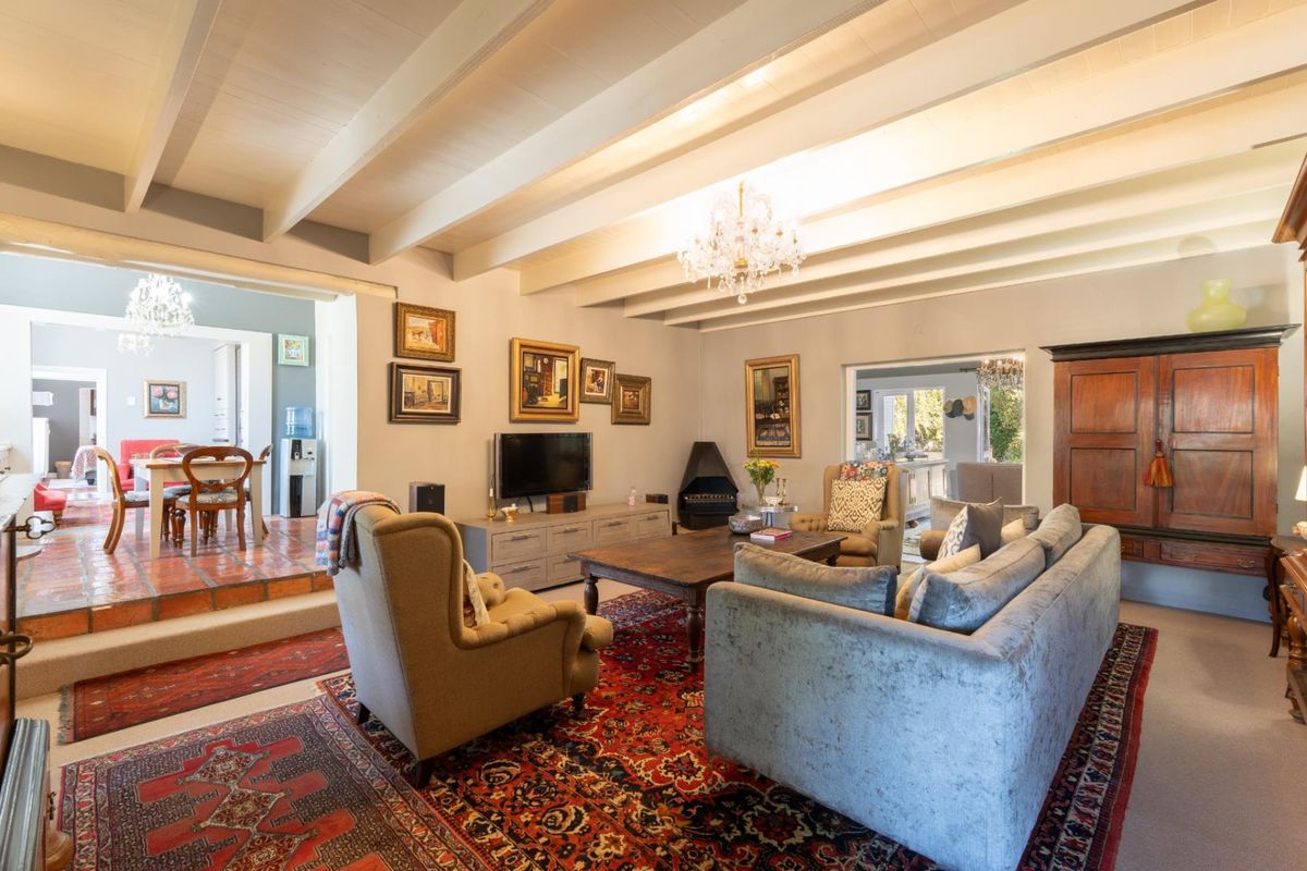 Spacious living room featuring exposed beam ceilings, a fireplace, and a split-level layout connecting to the dining area.