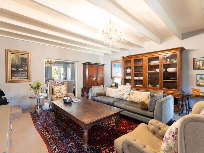 A cozy living room featuring an exposed beam ceiling, a traditional fireplace, and a classic chandelier, creating a warm and inviting atmosphere.