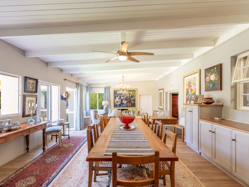 Spacious dining room featuring exposed beam ceilings, timber flooring, built-in cabinetry, and direct access to the outdoor area through sliding glass doors.