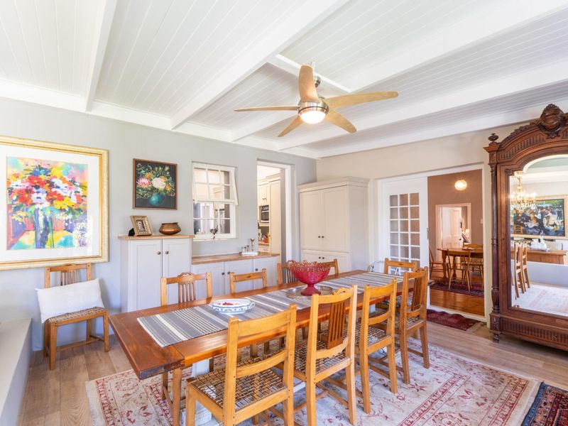 A well-maintained dining room featuring exposed beam ceilings, timber flooring, and built-in cabinetry, with french doors leading to an adjacent living space.